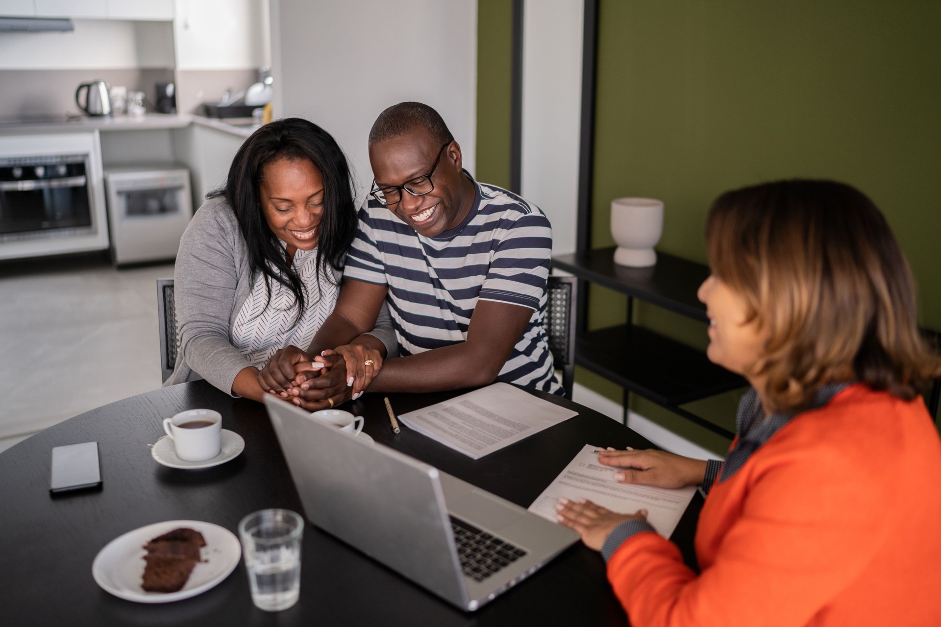 Feliz pareja celebrando la compra de una casa nueva con agente de bienes raíces