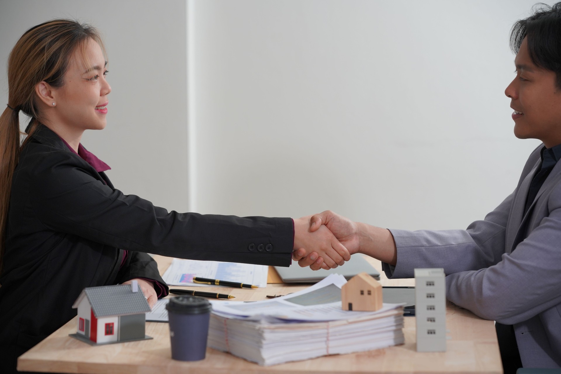 Un agente inmobiliario asiático estrecha la mano de un cliente después de cerrar con éxito la venta de una casa después de firmar un contrato para una nueva casa. que representa el éxito